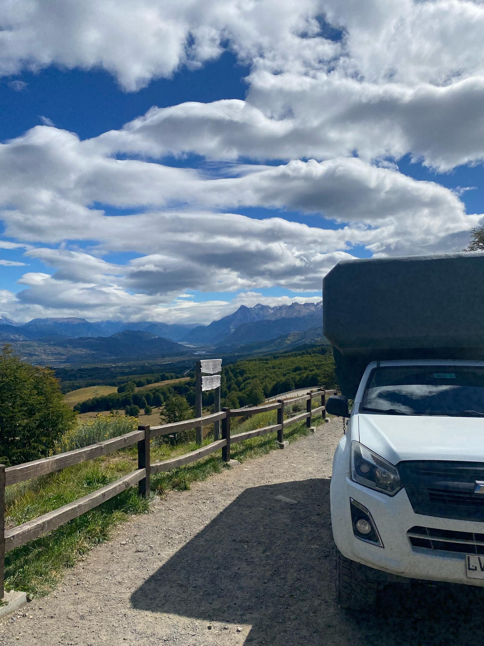 4x4 camper truck stopped at a gravel viewpoint above a valley
