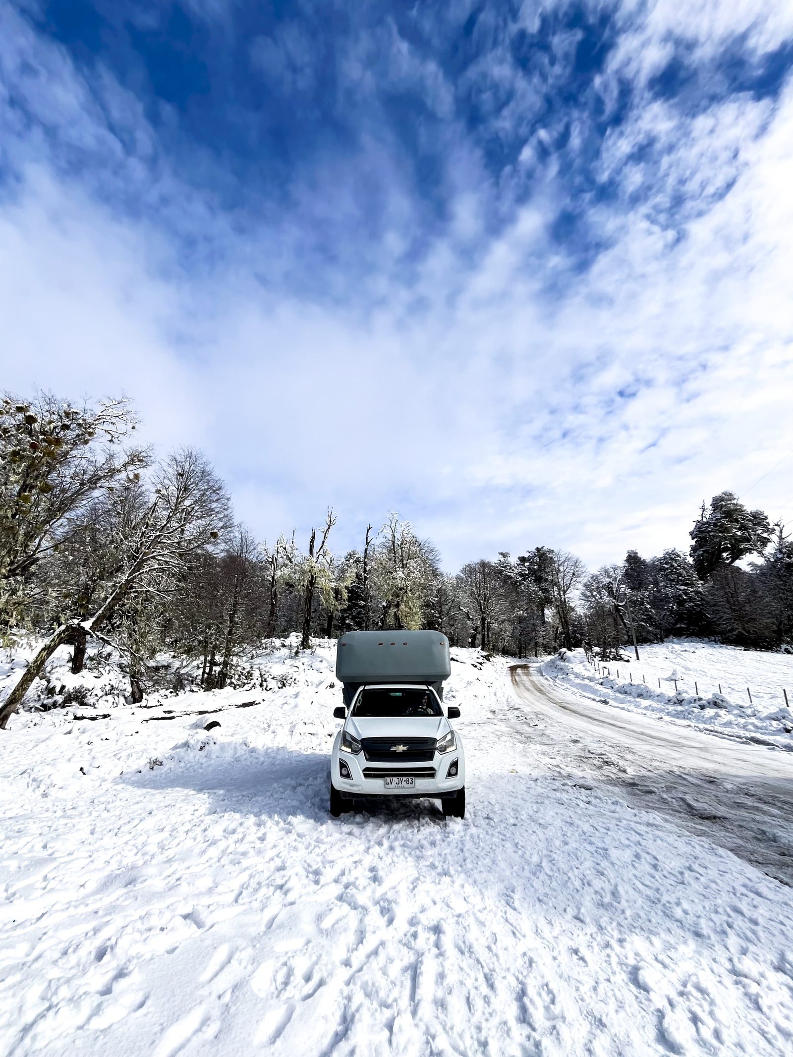 4x4 camper truck on a snow-covered road through snowy forest in winter