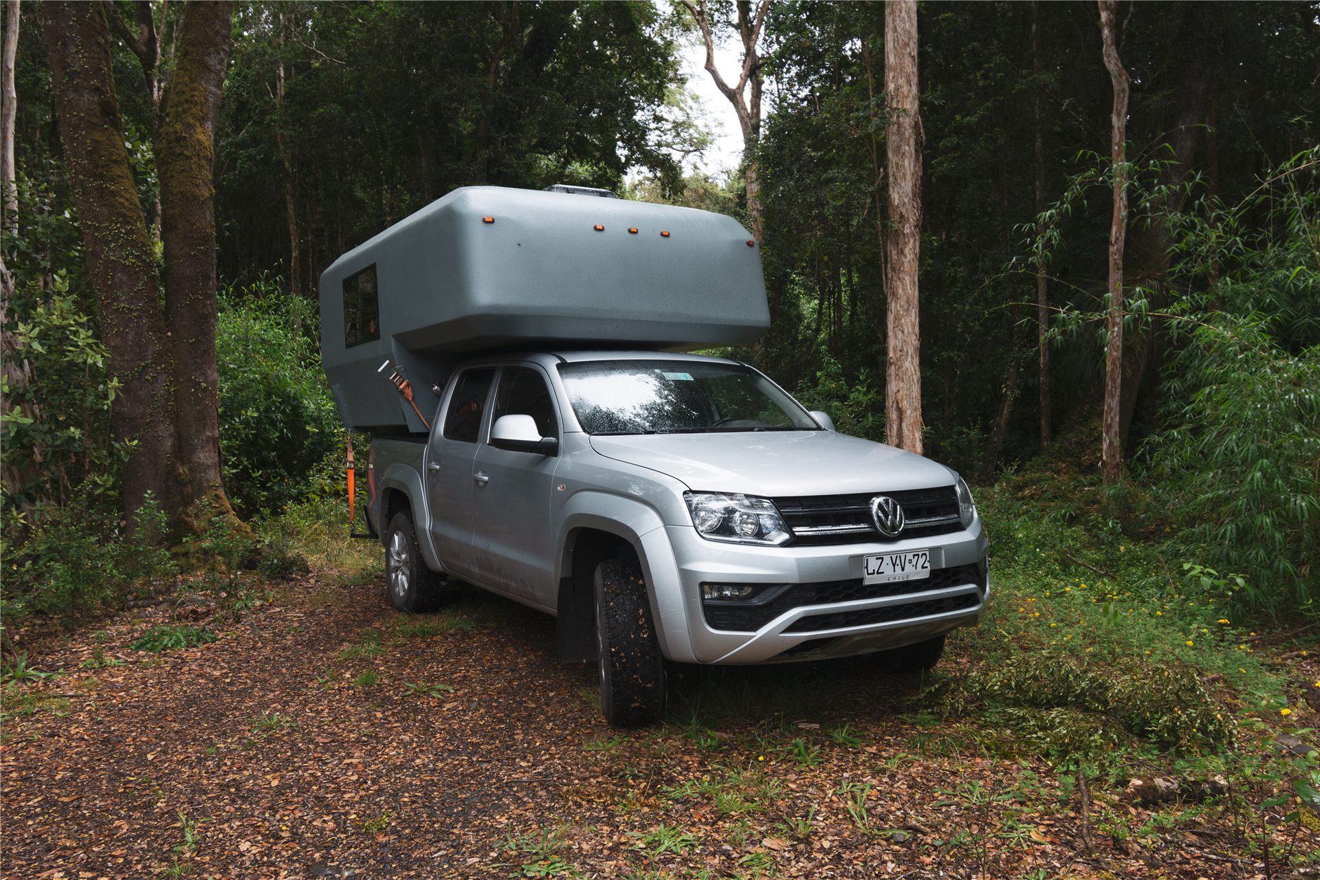 4x4 camper truck mounted on a pickup, parked in native forest in southern Chile