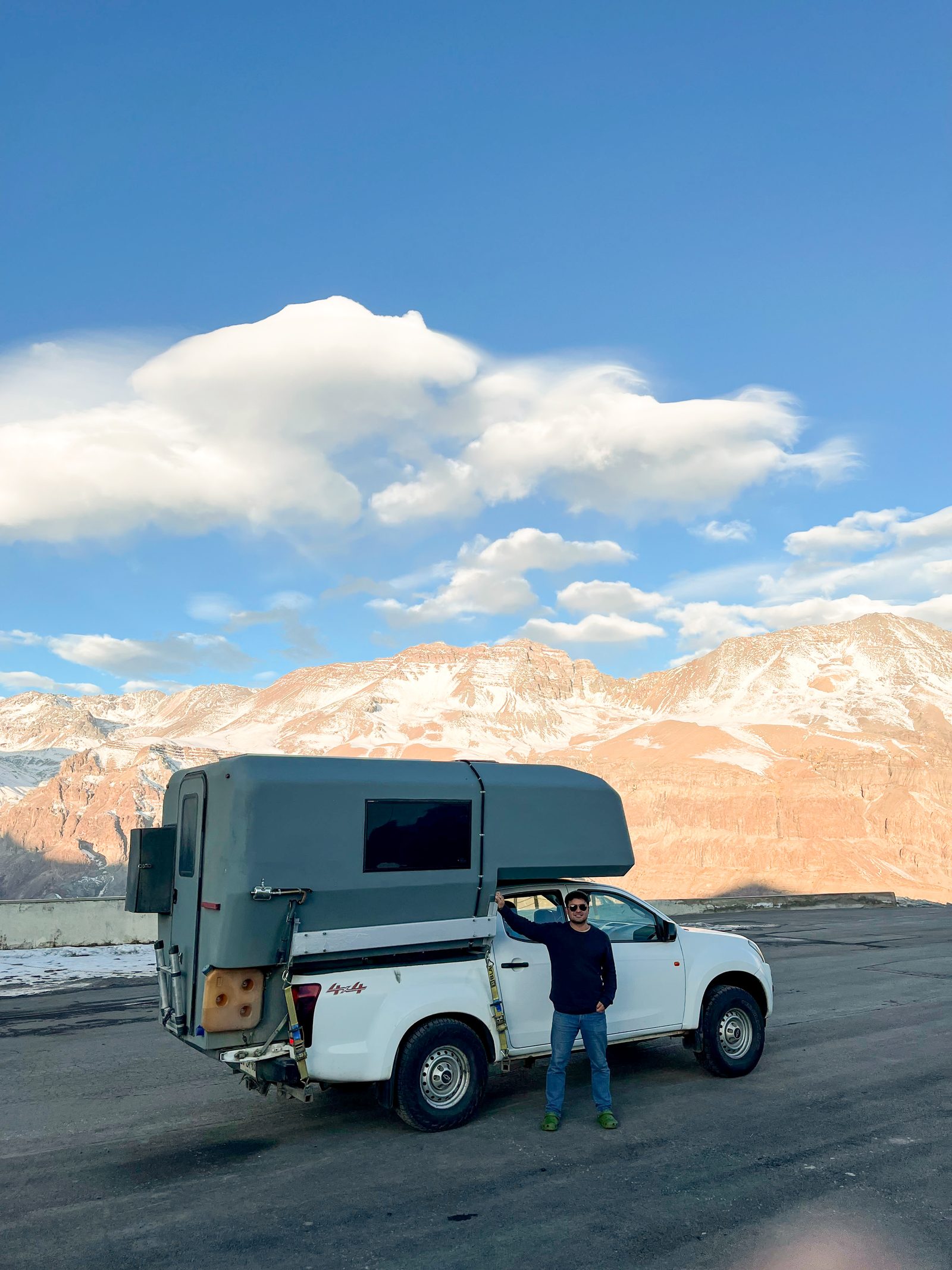 Rodrigo from South Nomads Campers beside a 4x4 camper truck in the mountains